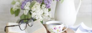 Glasses on top of a book sitting next to a tea cup