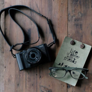 Camera and glasses on a table with a sign that reads Life is Better with Friends