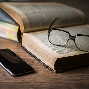 glasses sitting on top of a book next to a cell phone