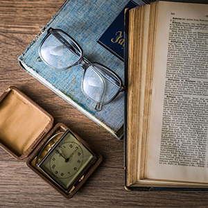 glasses, a book and a vintage clock sitting on a table