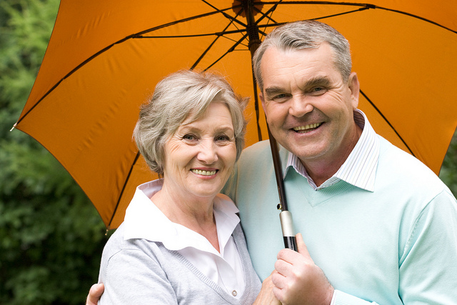 Portrait of happy senior couple under umbrella during rain