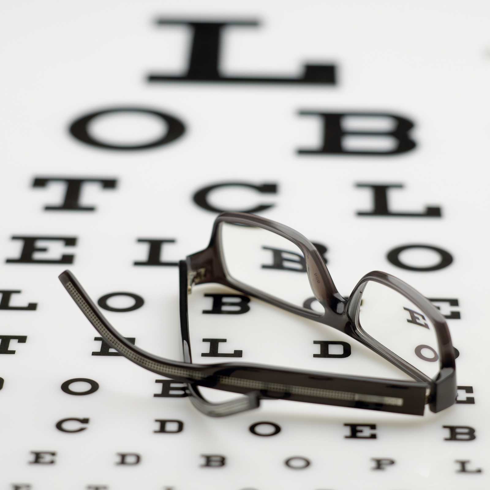 An eye chart with eyeglasses laying on top
