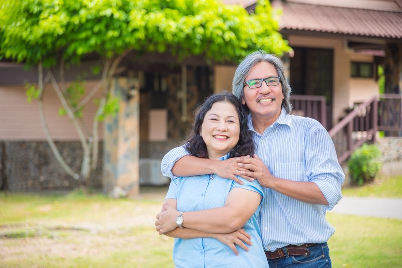 A happy couple standing in front of a house
