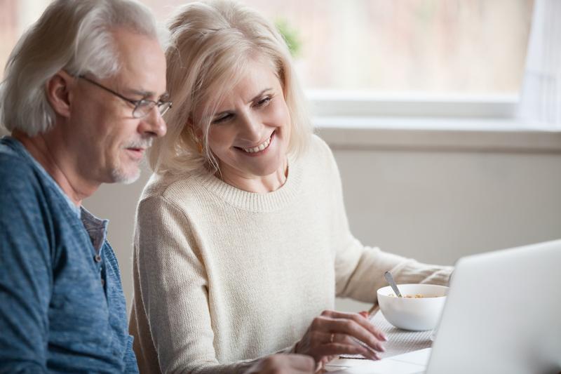 Older adult man and woman looking at a laptop together