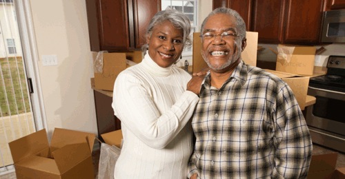 Mature couple posing in front of moving boxes in a kitchen