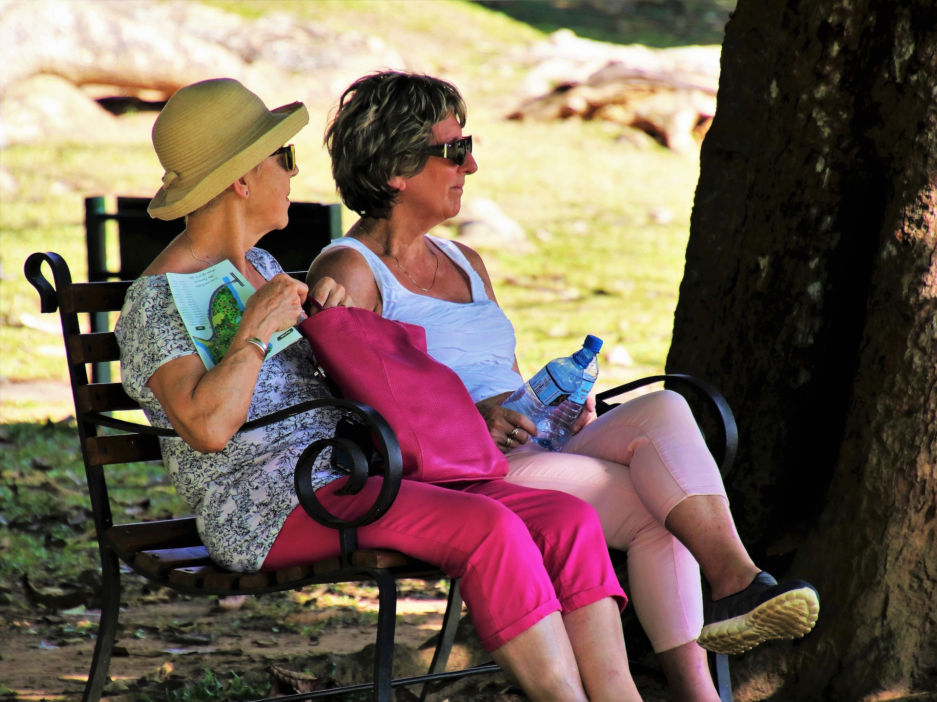 Two senior women sit on a park bench